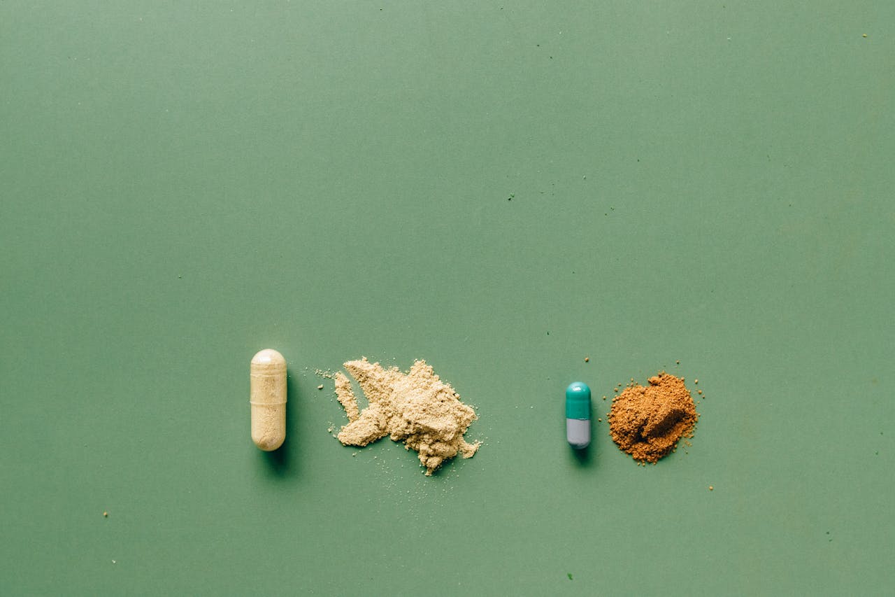 Variety of capsules and powders showcasing natural and pharmaceutical remedies on a green backdrop.